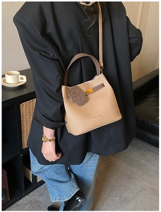 Détail du sac seau kaki avec poignées contrastées marron et breloque ours