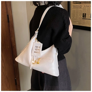 Detail of white textured leather hobo bag featuring gold hardware and fashion tag pendant