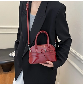 Close-up of a glossy deep red patent leather shell bag with silver buckle detail