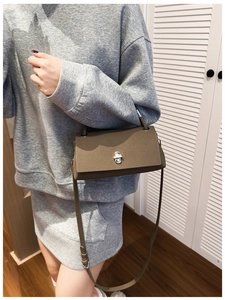 Detail of dark olive pebble leather crossbody bag with silver twist lock and slim strap