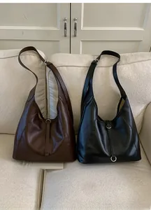 Close-up of minimalist soft leather tote bags with metal ring buckle in brown and black