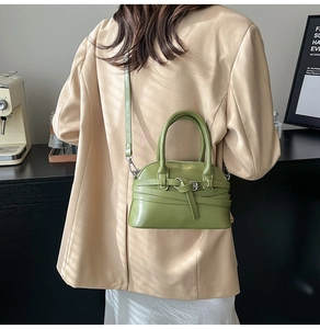 Model wearing a green leather crossbody bag in a cozy indoor cafe with natural window shadows