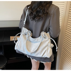 Close-up of a soft grey leather tote bag with drawstring detail and adjustable strap