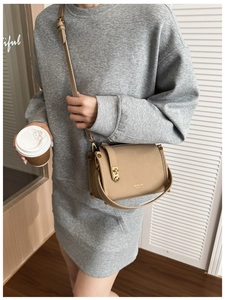 Schicke beige strukturierte Umhängetasche mit Goldschnalle, getragen von einem Model