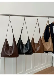 Four leather tote bags in dark brown, black, caramel, and beige colors hanging on a rack