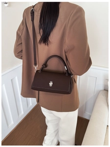 Detailed view of dark brown pebbled leather square bag with silver twist lock and strap