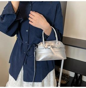 Detail view of silver metallic textured crossbody bag with top handle and strap