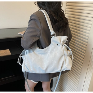 Detail of light blue soft leather tote bag with side drawstring and long shoulder strap