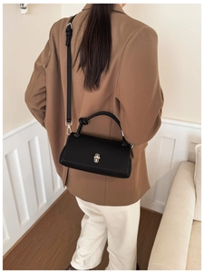 Detail of black lychee texture leather handbag with silver twist lock and knotted handle