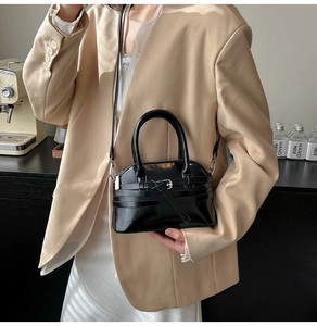Chic black patent leather handbag shown on model with elegant almond suit and white dress