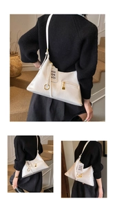Detail of white glossy leather hobo bag featuring metal ring zipper and fashion brand tag