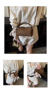 Detailansicht der dunkelbraunen Boston-Tasche mit Litschi-Textur und Kaninchen-Anhänger