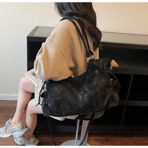 Close-up of a large black matte leather tote bag with drawstring and silver hardware details