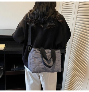 Détail du sac fourre-tout gris matelassé avec broderie losange et bandoulière noire