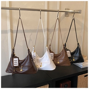 Close-up of four minimalist faux leather tote bags in various colors on a display rack