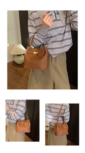 Détail du sac seau en cuir marron avec fermoir doré et breloque ours amovible
