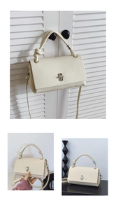 Detail of cream white pebbled leather bag with knotted handle and silver metal clasp