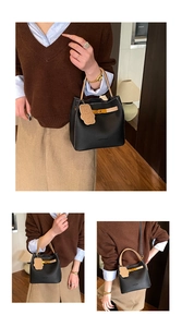 Détail du sac seau en cuir grainé noir avec poignées beiges et breloque en forme d'ours