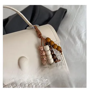 Close-up of a cream woven leather handbag with a colorful wooden beaded keychain