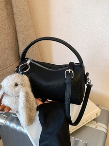 Minimalistische schwarze Boston Bag aus Leder mit Plüschhasen-Anhänger auf Silberkoffer