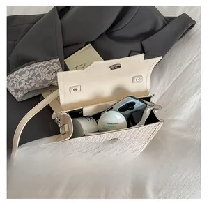 Interior view showing the capacity of this cream woven crossbody bag with daily essentials