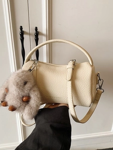 Schicke beige Boston-Handtasche mit Plüsch-Hasenanhänger und Umhängeriemen in der Hand