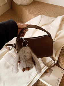 Minimalistische braune Boston Bag mit Plüschkaninchen auf weißem Anzug