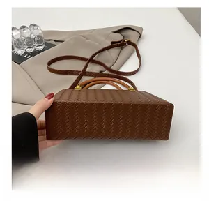 Detail showing the reinforced bottom and woven texture of the brown handbag
