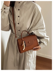 Detail of vintage brown hand-woven bag with smooth leather flap and decorative wood beads