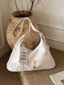White pleated leather hobo bag with gold hardware and adjustable strap on a vintage background