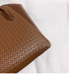 Close-up of brown woven leather texture with diagonal checkerboard pattern on the tote bag