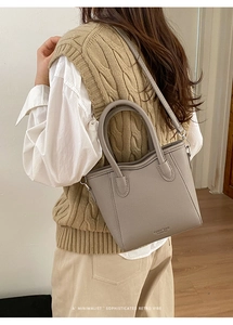 Brownish grey lychee grain leather bucket bag shown on model with shoulder strap