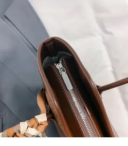 Close-up of top zipper closure on brown woven tote bag with decorative silk scarf