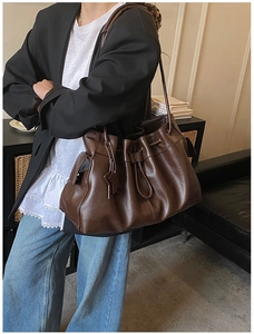 Detail of soft brown leather drawstring bucket bag with star pendant on a model