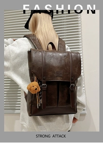 Detail of vintage brown leather backpack featuring metal buckle straps and a cute plush bear