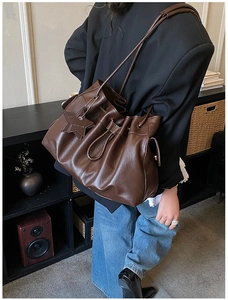 Detail of dark brown drawstring bucket bag with star charm and soft pleated texture