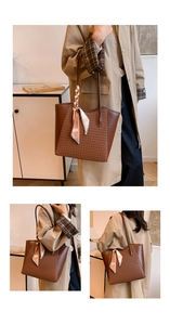 Close-up of brown woven tote bag with smooth leather sides and stylish silk scarf on handle