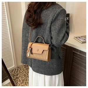 Detail of camel retro small square bag with woven panel and bead tassel charm on a model