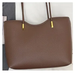 Detail of dark brown pebbled leather tote showing wavy edge and golden metal hardware