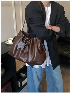 Detail of dark brown leather drawstring bucket bag with star-shaped metal pendant