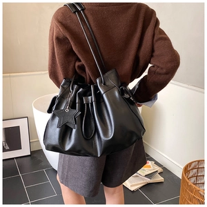 Detail of black drawstring bucket bag with star pendant shown in a lifestyle setting