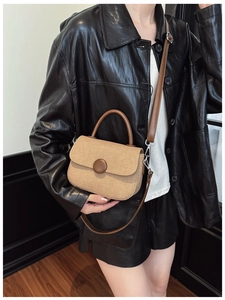 Detail of khaki canvas crossbody bag with brown leather trim and retro round button