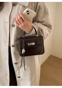 Details der dunkelbraunen Lederhandtasche mit silbernem Drehverschluss und Herzanhänger
