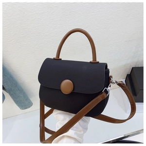 Detail of a retro fabric handbag with brown leather handles and decorative round buckle