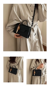 Detail of black vintage crossbody bag with woven texture and ethnic wooden bead charm