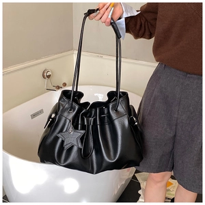Side view of black drawstring bucket bag with star pendant on a female model