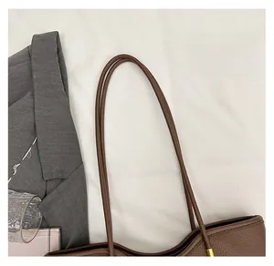Close-up of the long leather handles on this vintage brown litchi pattern tote bag