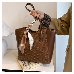 Detail of dark brown woven tote bag with fashion scarf handle and spacious interior