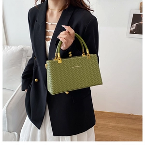 Detailed view of avocado green woven handbag featuring golden metallic handle base