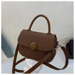 Close-up of dark brown canvas handbag with vintage round buckle and silver hardware